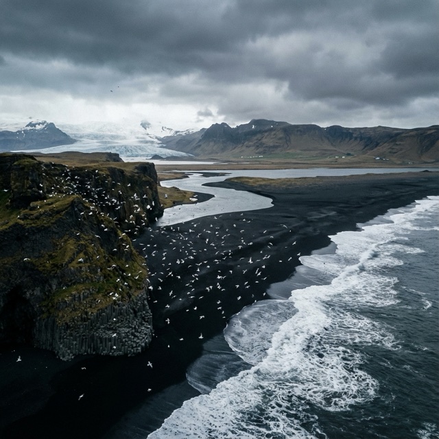 Test still of a black beach, glacier, surf, and birds under dark clouds