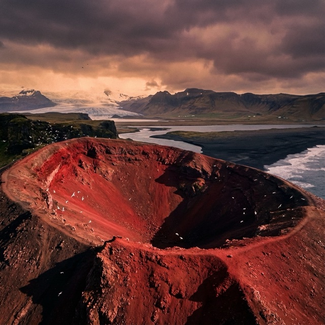 Test still of a red crater above a dark coast at dusk